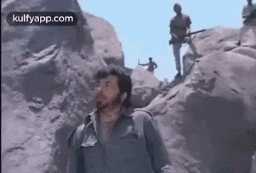 a man is standing on top of a rocky cliff .