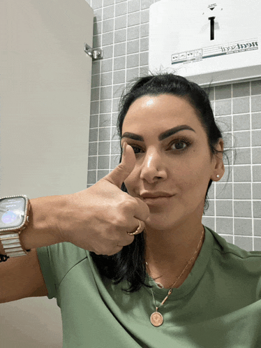 a woman giving a thumbs up in front of a paper towel dispenser that says ' hygiene ' on it