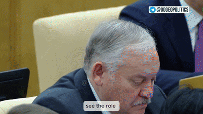 a man with gray hair and a mustache is sitting in front of a screen that says see the role on it