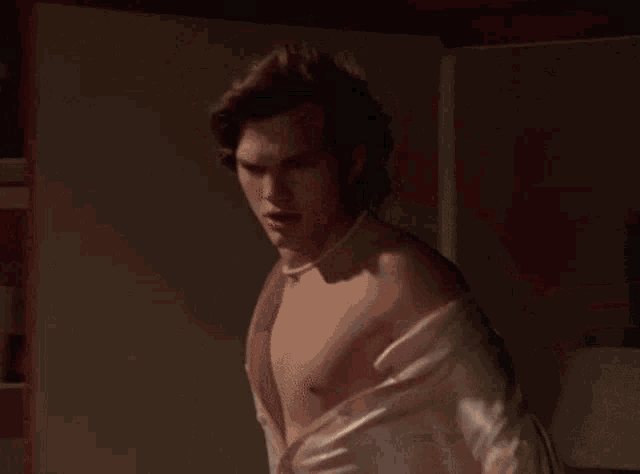 a man without a shirt is wearing a pearl choker