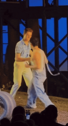 two men are standing on a stage and one has a microphone