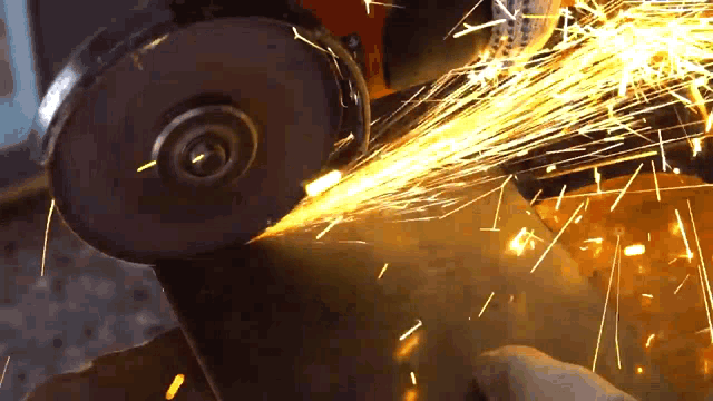 a person is grinding a piece of metal with sparks flying