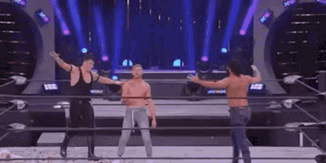 a group of men are standing in a wrestling ring with their arms outstretched