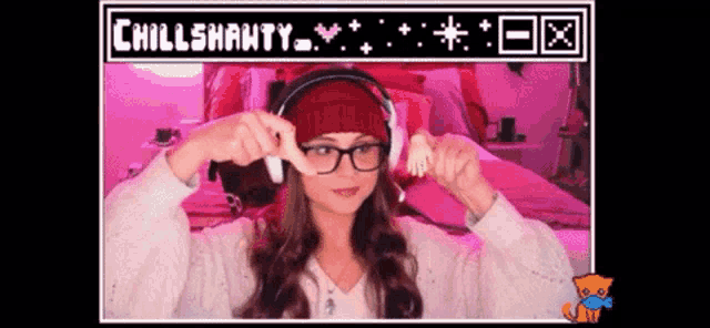 a woman wearing headphones and a red beanie is holding a small hand in front of a screen that says chillshanty