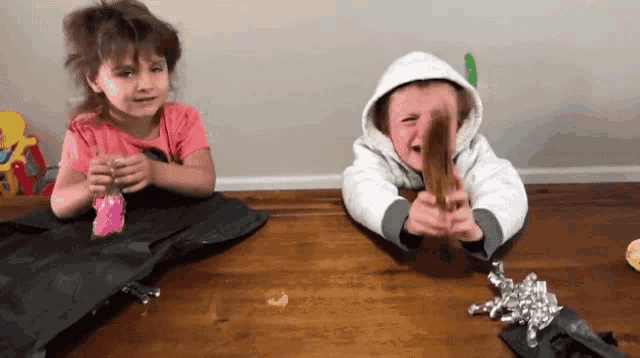 a boy and a girl sitting on a wooden table
