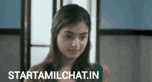 a woman is standing in front of a window with the words startamilchat.in written on the bottom