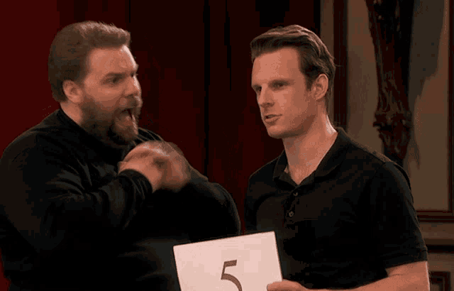 a man is holding a sign that says 5 on it