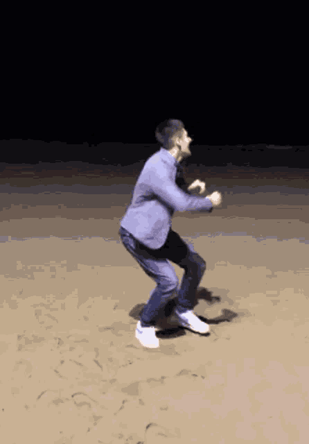 a man in a suit is dancing on the sand