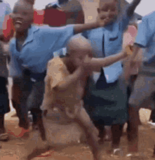 a group of people in blue shirts are dancing in a crowd .