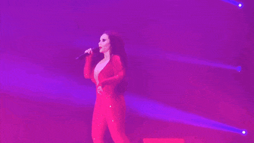 a woman is dancing on stage in front of a purple light .