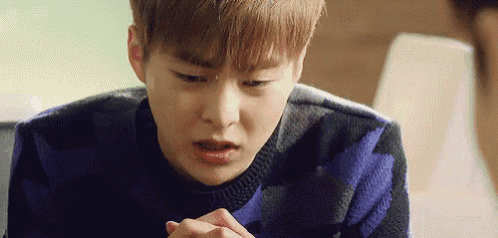 a close up of a young man wearing a sweater and making a funny face .