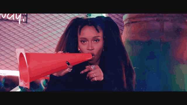 a woman with dreadlocks is blowing into a red cone