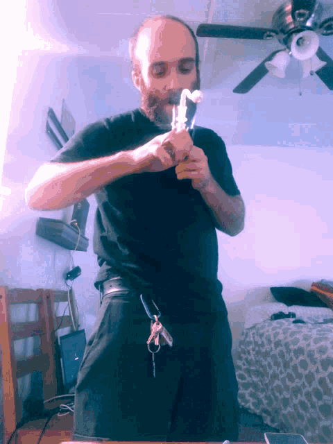 a man with a beard is smoking a pipe in a room with a ceiling fan
