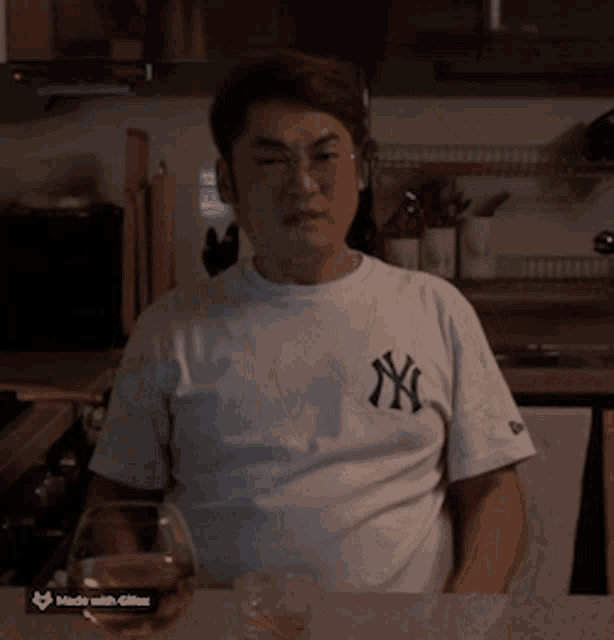 a man wearing a ny yankees shirt sits at a counter