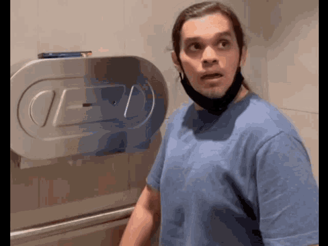 a man wearing a blue shirt and a black mask stands in front of a paper towel dispenser that says oed