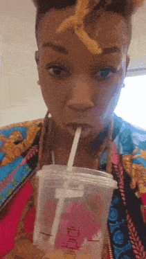 a woman drinking from a plastic cup with a straw that says libra
