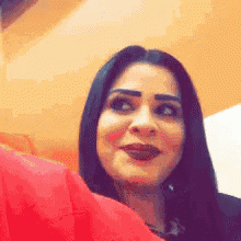a close up of a woman 's face with a red blanket in the background .