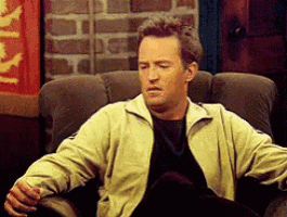 a man is sitting in a chair with a brick wall behind him and a sign that says ' a ' on it