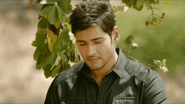 a man in a black shirt is standing in front of a tree
