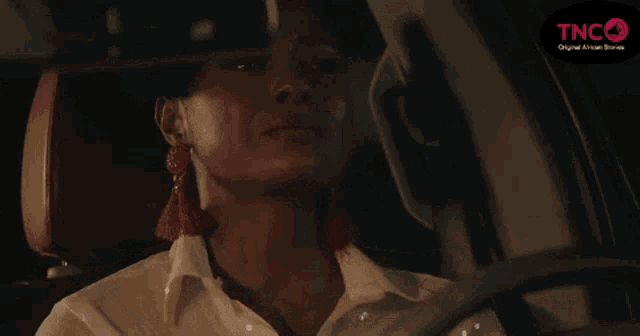 a woman is sitting in the driver 's seat of a car at night .