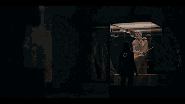 a person holding a flashlight in front of a statue in a dark room