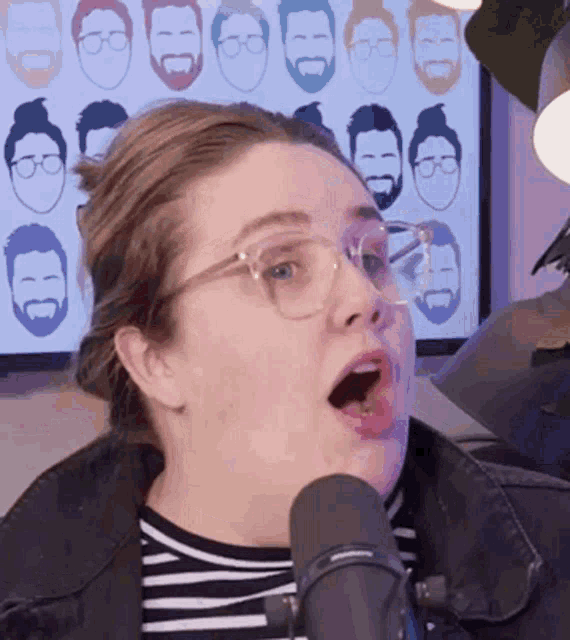 a woman wearing glasses is singing into a microphone with her mouth wide open