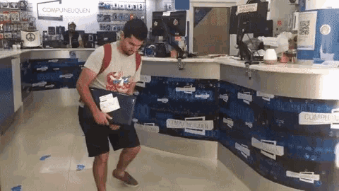 a man is carrying a laptop in front of a comptineuquen counter