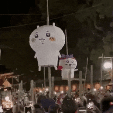 a group of people are watching a cartoon character hanging from a rope .