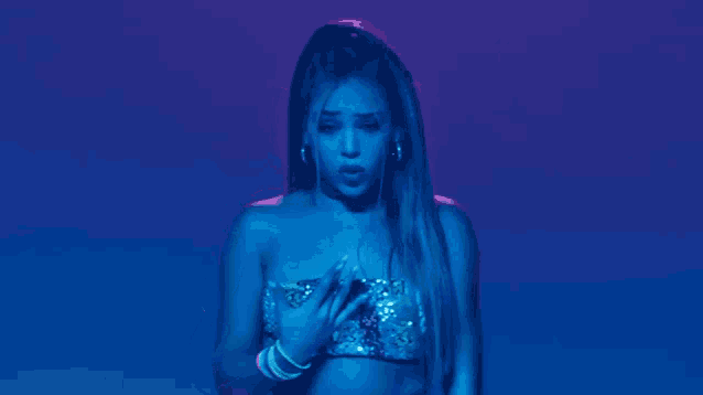 a woman wearing a sequined top and neon bracelets is making a rock sign