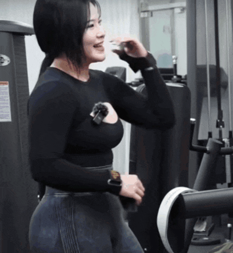 a woman in a black shirt is standing in front of a machine that has a warning label on it