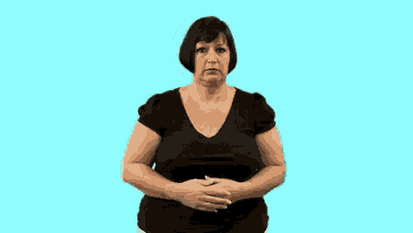 a woman in a black shirt is standing in front of a blue background with her hands on her hips .