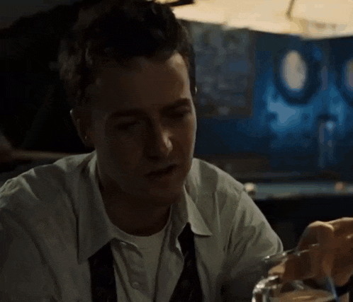 a man in a white shirt and tie is drinking a glass of water