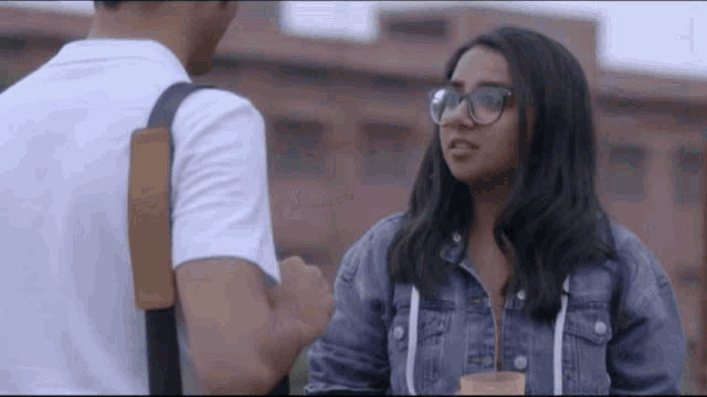 a man and a woman are standing next to each other and the woman is wearing glasses .