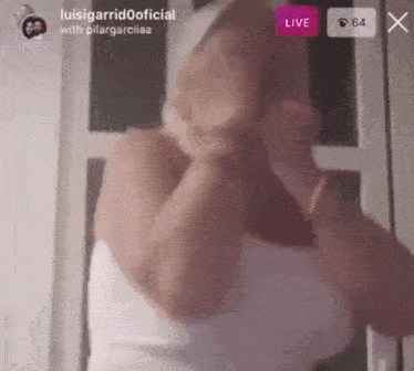 a woman in a white tank top is dancing in front of a live audience