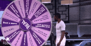 a man is standing in front of a wheel that says real