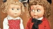 two dolls , one girl and one boy , are sitting next to each other .