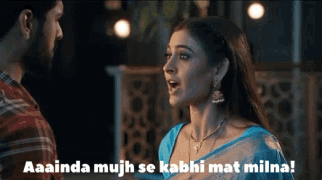 a woman in a blue saree is talking to a man in a red shirt .