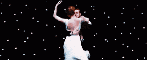 a man and a woman are dancing in front of a starry sky .