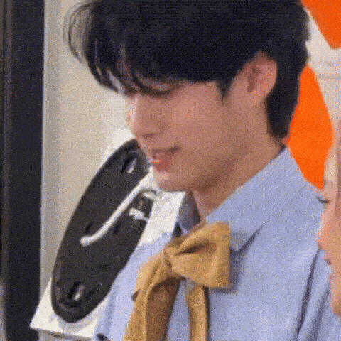 a young man wearing a blue shirt and a yellow tie is standing in front of a washing machine .