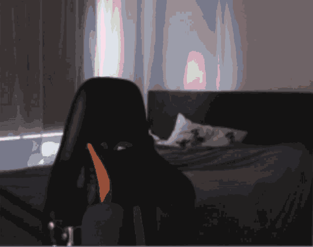 a blurred image of a bedroom with a bed and a chair in the foreground