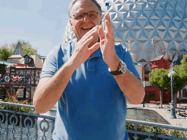 a man in a blue shirt is clapping his hands in front of a building that says ' eiffel tower '