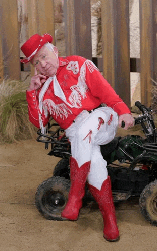 a man in a red and white cowboy outfit is sitting on a motorcycle