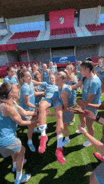 a group of female soccer players are standing in a circle on the field