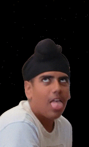 a man wearing a turban and a white shirt is sticking his tongue out