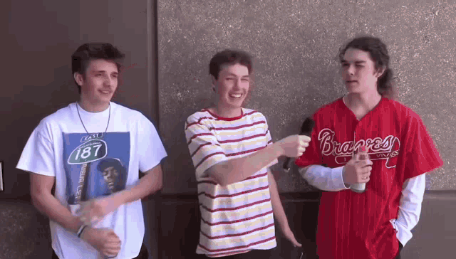three young men are standing next to each other and one has a braves jersey on
