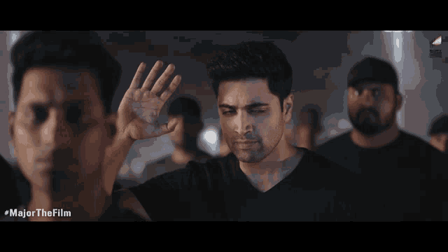 a man in a black shirt is waving his hand in front of a group of men with the caption major the film