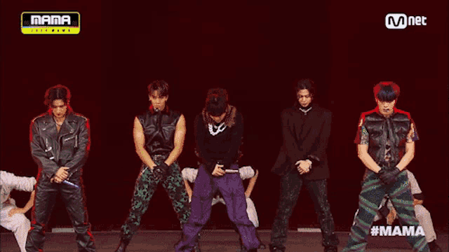 a group of young men are dancing on a stage with a mnet logo in the background