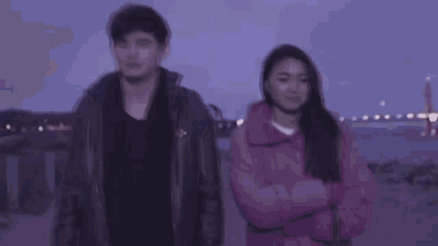 a man and a woman standing next to each other with their arms crossed .