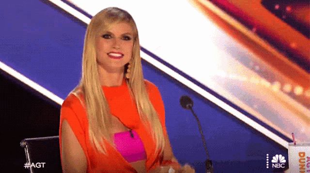 a woman sitting in front of a microphone with the word agt on the bottom right