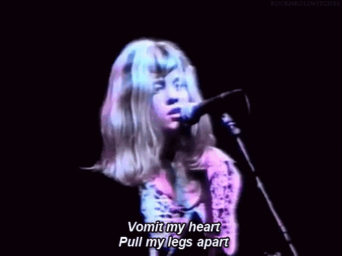 a woman singing into a microphone with the words vomit my heart pull my legs apart written below her